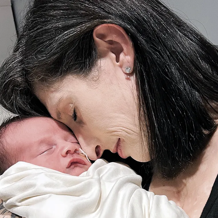 A woman holding a newborn cheek to cheek